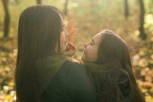 pequeño niña jugando con madre en el otoño parque foto