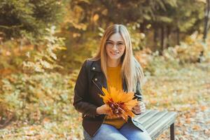 Girl holds fallen leaves in autumn park. Seasonal concept. photo