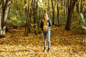 Portrait of beautiful woman holds autumn leaves. Stylish youth and fall season concept. photo