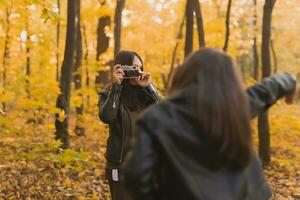 madre tomando imagen su carismático hija en retro cámara en otoño parque. aficiones y ocio concepto. foto