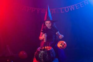 Little witch child cooking potion in the cauldron on Halloween. photo