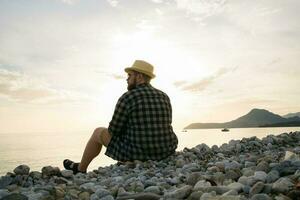 Rear view of man sitting on beach on sunny day outside background - vacation or freelance travel concept photo