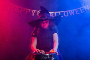 Little witch child cooking potion in the cauldron on Halloween. photo