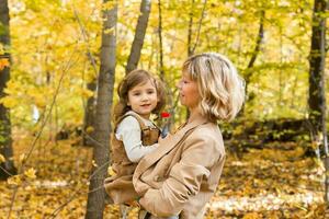 Mother with child in her arms against background of autumn nature. Family and season concept. photo