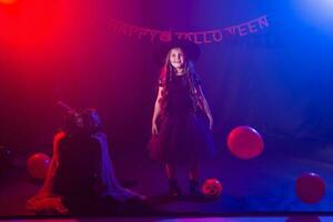 Funny child girl in witch costume for Halloween with pumpkin Jack. photo