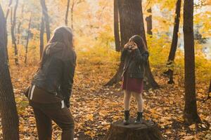 niño tomando imagen su madre en retro cámara en otoño parque. aficiones y ocio concepto. foto