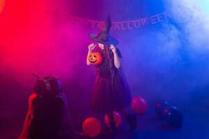 gracioso niño niña en bruja disfraz para Víspera de Todos los Santos con calabaza Jacobo. foto