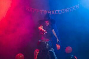 Child girl witch preparing a potion in the cauldron at halloween holidays. photo