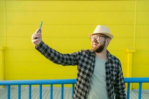 Man telling something at the camera while traveling at new city, yellow supermarket background. Blogger and vlog concept photo
