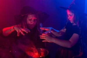 Funny child girl and woman in witches costumes for Halloween. photo