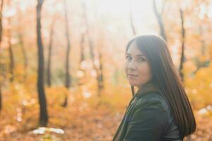 Asian brunette woman standing in a park in autumn. Fall and season concept. photo