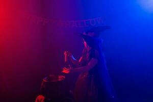 Child girl witch preparing a potion in the cauldron at halloween holidays. Copy space. photo