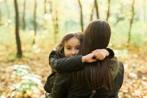 Mother and daughter spend time together in autumn yellow park. Season and single parent concept. photo