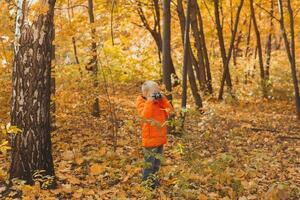 Boy with retro camera taking pictures outdoor in autumn nature. Leisure and photographers concept photo