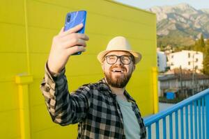 Man telling something at the camera while traveling at new city, yellow supermarket background. Blogger and vlog concept photo