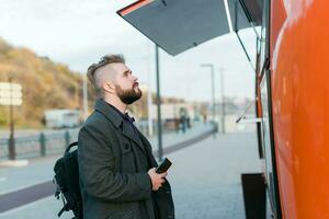 Portrait of man choosing fast food in food truck in the street. Meal, food industry and streetfood concept. photo