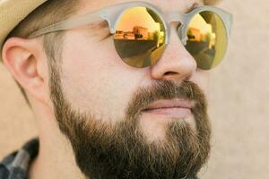 Close up portrait handsome man wearing sunglasses near wall - travel vacations and summer holiday concept photo