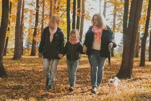 Grandmother and mother with granddaughter walks together in autumn park and having fun. Generation, leisure and family concept. photo