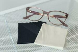 Glasses and rag for lens wipes on shelf - accessories for eyeglasses photo