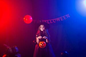 Funny child girl in witch costume for Halloween with pumpkin Jack. photo