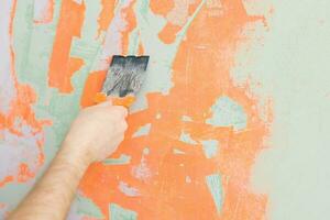 Close Up view of a man's hand plastering hole in a wall with spatula photo