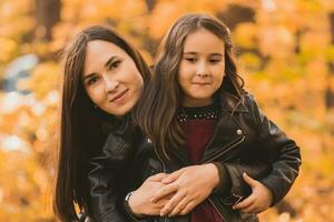 retrato hija jugando con madre en el otoño parque - otoño y familia concepto foto