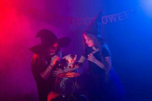 Two halloween witches making magic with dog jack russell terrier in halloween night. Magic, holidays and mystic concept. photo