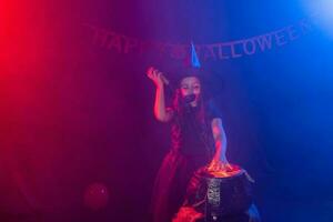 Little witch child cooking potion in the cauldron on Halloween. photo