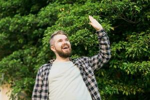 Side view of delighted male standing outdoors and waving hand to his friend. He is joyful to meet his acquainted by chance. photo