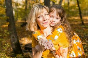 joven madre con su pequeño hija en un otoño parque. otoño estación, paternidad y niños concepto. foto