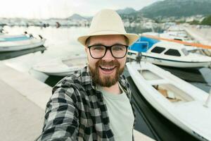 viajero hombre tomando selfie de lujo yates marina durante soleado día - viaje y verano concepto foto