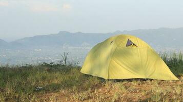 Camping tent on a hill with mountains in the background in the morning photo