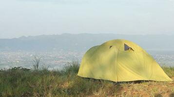 Camping tent on a hill with mountains in the background in the morning photo