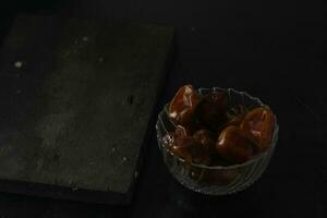 Bowl of dried dates isolated on black background photo