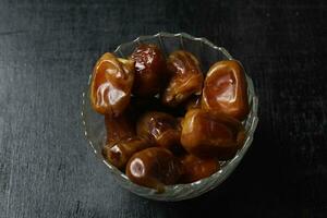 Bowl of dried dates isolated on black background photo