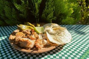 el mexicano Carnitas plato es servido en un mesa, adornado con vajilla y Manteles foto