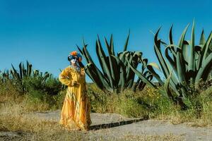 Mexican woman in colorful dress and skull makeup in the mexican desert cactus photo