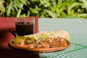 The Mexican carnitas, a delicious food, is served with various condiments on a table with tableware photo