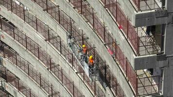 Construction workers on a suspended platform on a skyscraper video