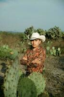 young man with mexican hat in a desert landscape with cactus photo