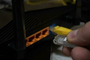 Close-up of a man's hand, fingers connecting a network cable to a router. photo