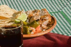 The Mexican carnitas, a delicious food, is served with various condiments on a table with tableware photo