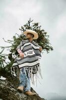 Cowboy wearing a poncho sitting under a tree in the sky photo