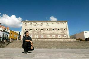 un hombre disfrutando el viaje experiencia cerca alhóndiga Delaware granaditas en guanajuato, México, debajo un nublado cielo foto