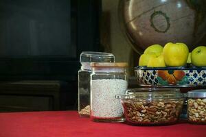 Containers with nuts, seeds and fruit on the table photo