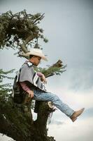 vaquero vistiendo un poncho sentado debajo un árbol en el cielo foto