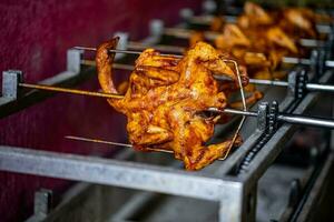 Close-up of roasting a whole chicken in a simple grill in Asia photo