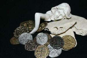 Mermaid laying On Shells Touching Coins From A Treasure Chest. photo