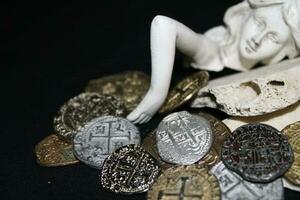 Mermaid laying On Shells Touching Coins From A Treasure Chest. photo