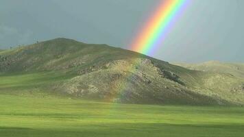 denso arco iris en sin árboles colina video